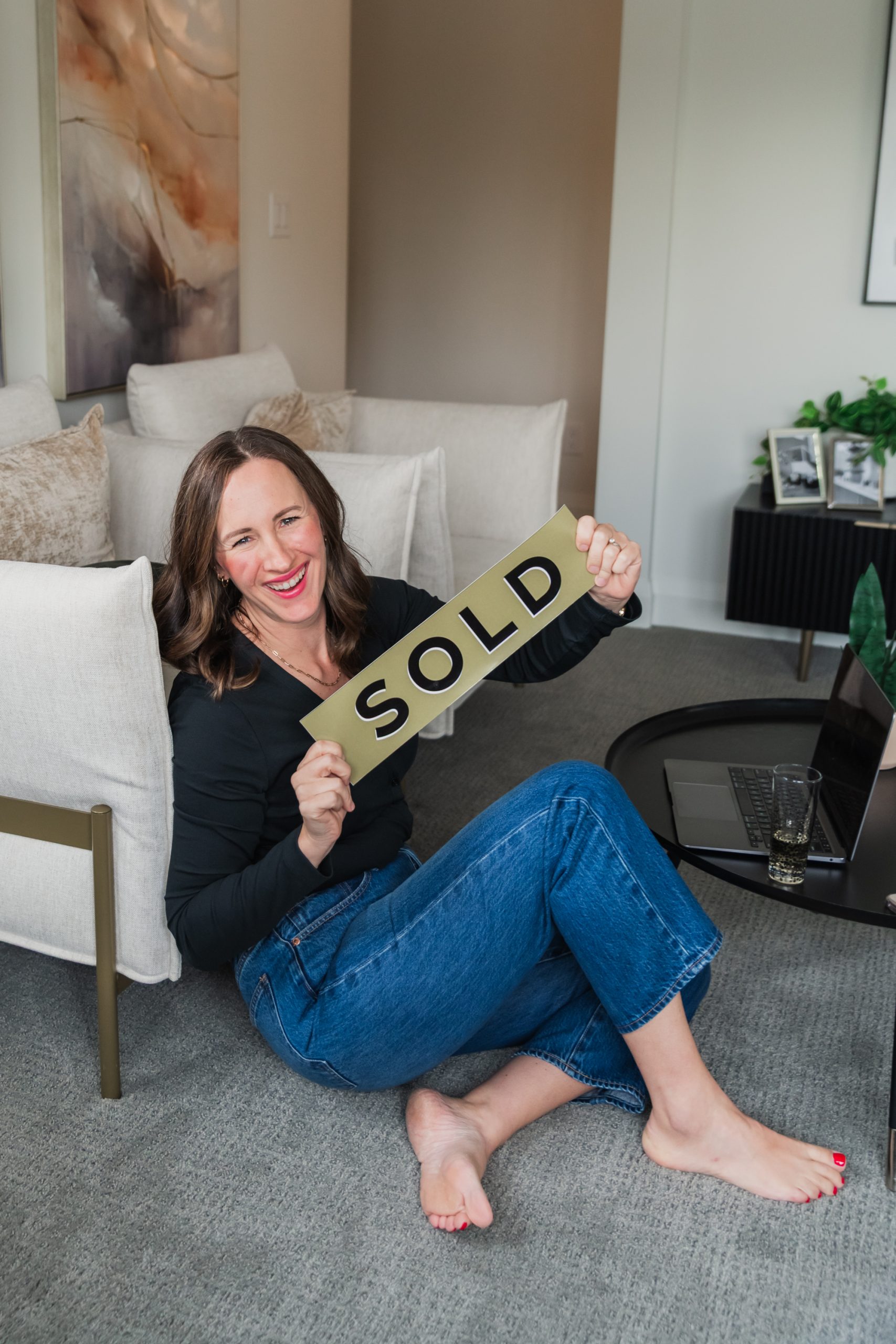 Ashley Tichkowsky with a sold sign in one of her real estate properties